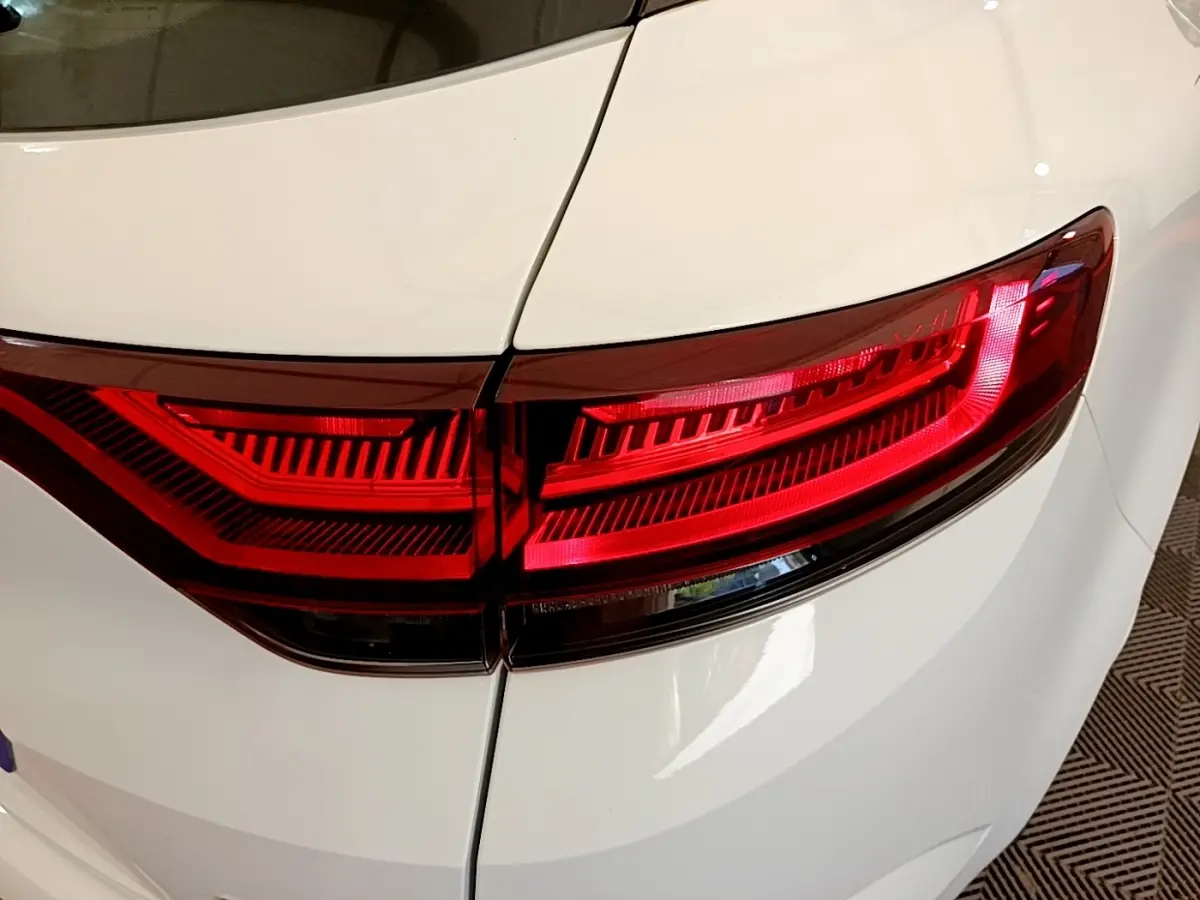 Gros plan sur le feu arrière droit rouge d’une Renault Mégane Business E-Tech hybride rechargeable blanche, vue arrière.