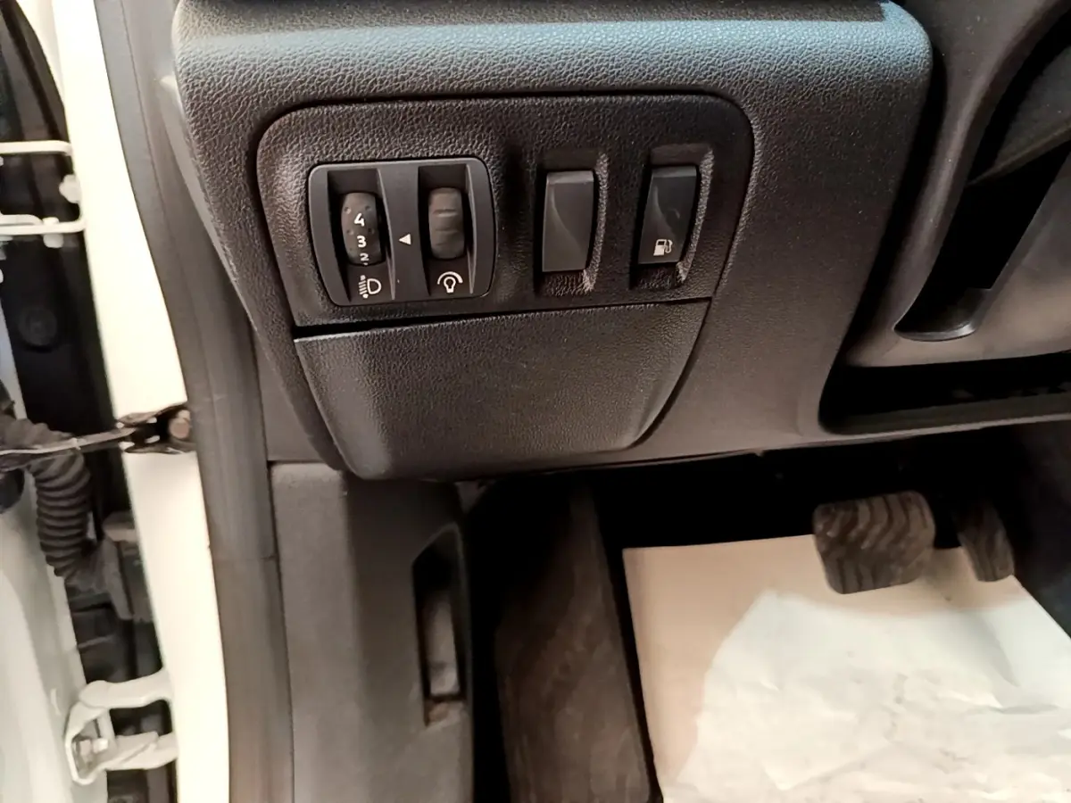 Vue rapprochée côté conducteur de la Renault Mégane Business E-Tech hybride blanche, montrant les commandes d’éclairage et ouverture carburant.