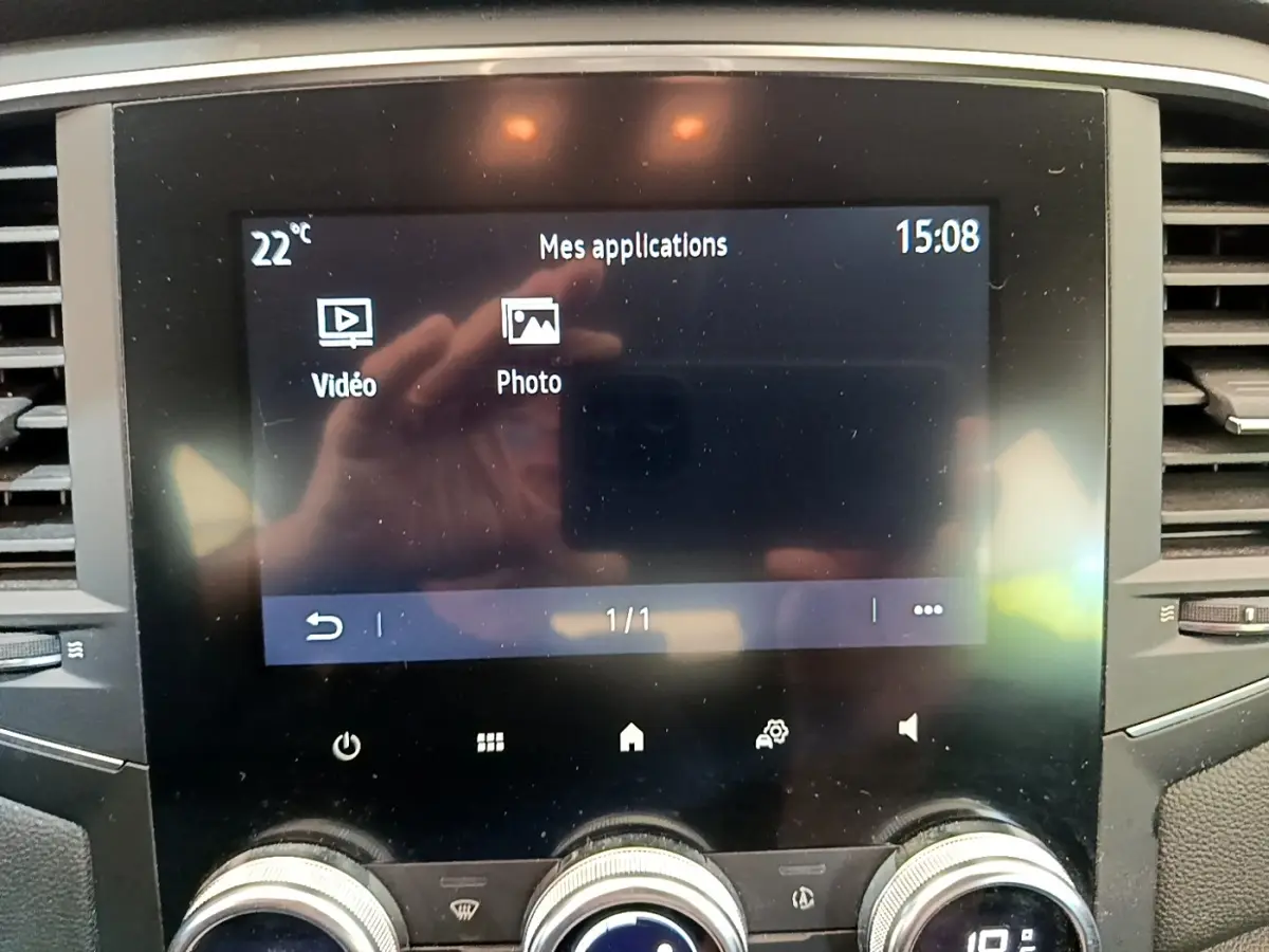 Écran tactile central affichant les applications vidéo et photo dans l’habitacle d’une Renault Mégane blanche hybride rechargeable.