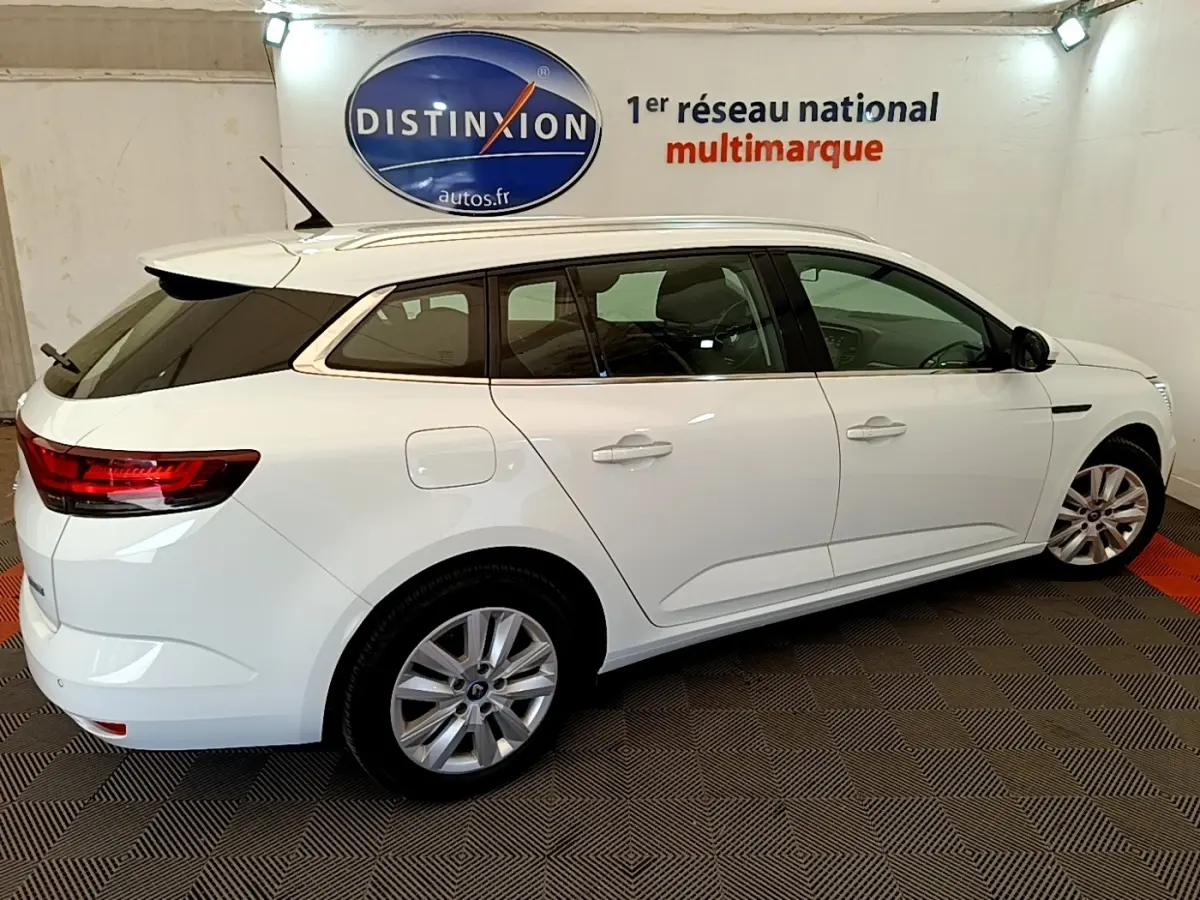 Renault Mégane Business E-Tech hybride blanche vue de profil droit en stationnement intérieur, jantes alliage visibles.