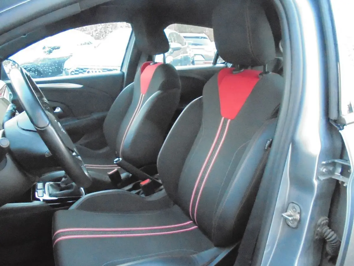 Vue intérieure côté conducteur de l’Opel Corsa gris quartz, sièges noirs avec inserts rouges et coutures contrastées.