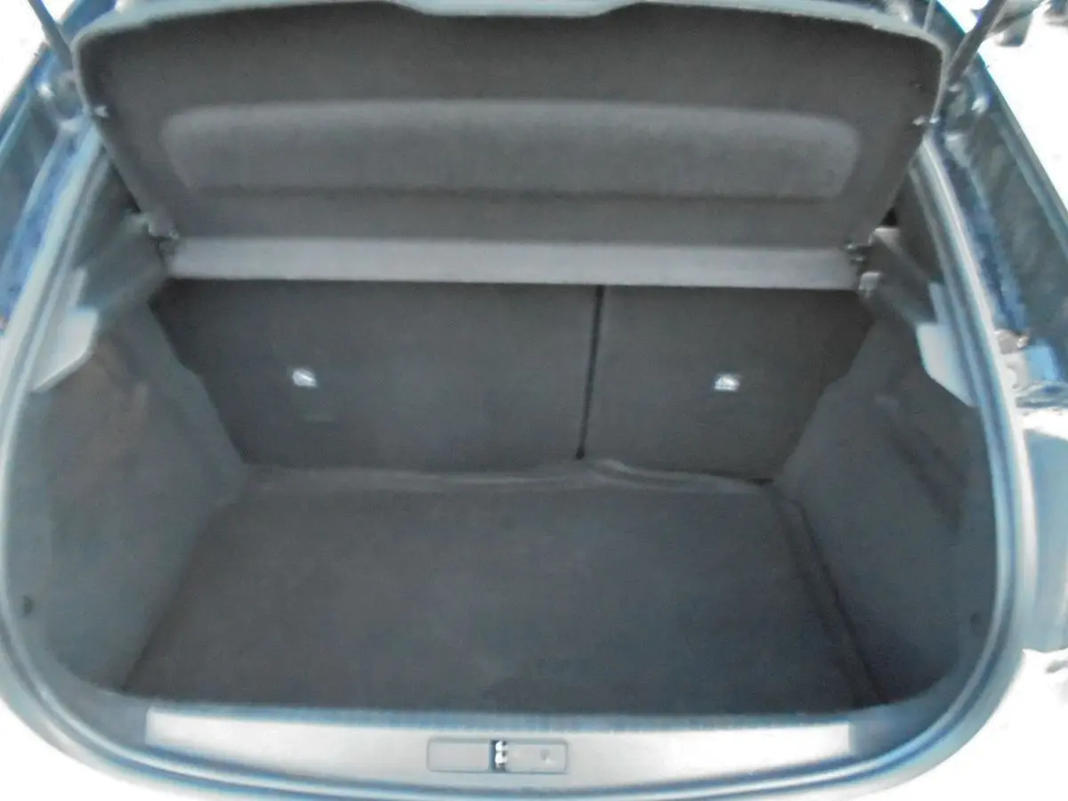 Coffre ouvert de l’Opel Corsa gris quartz metal, vue plongeante sur l’espace de chargement vide.