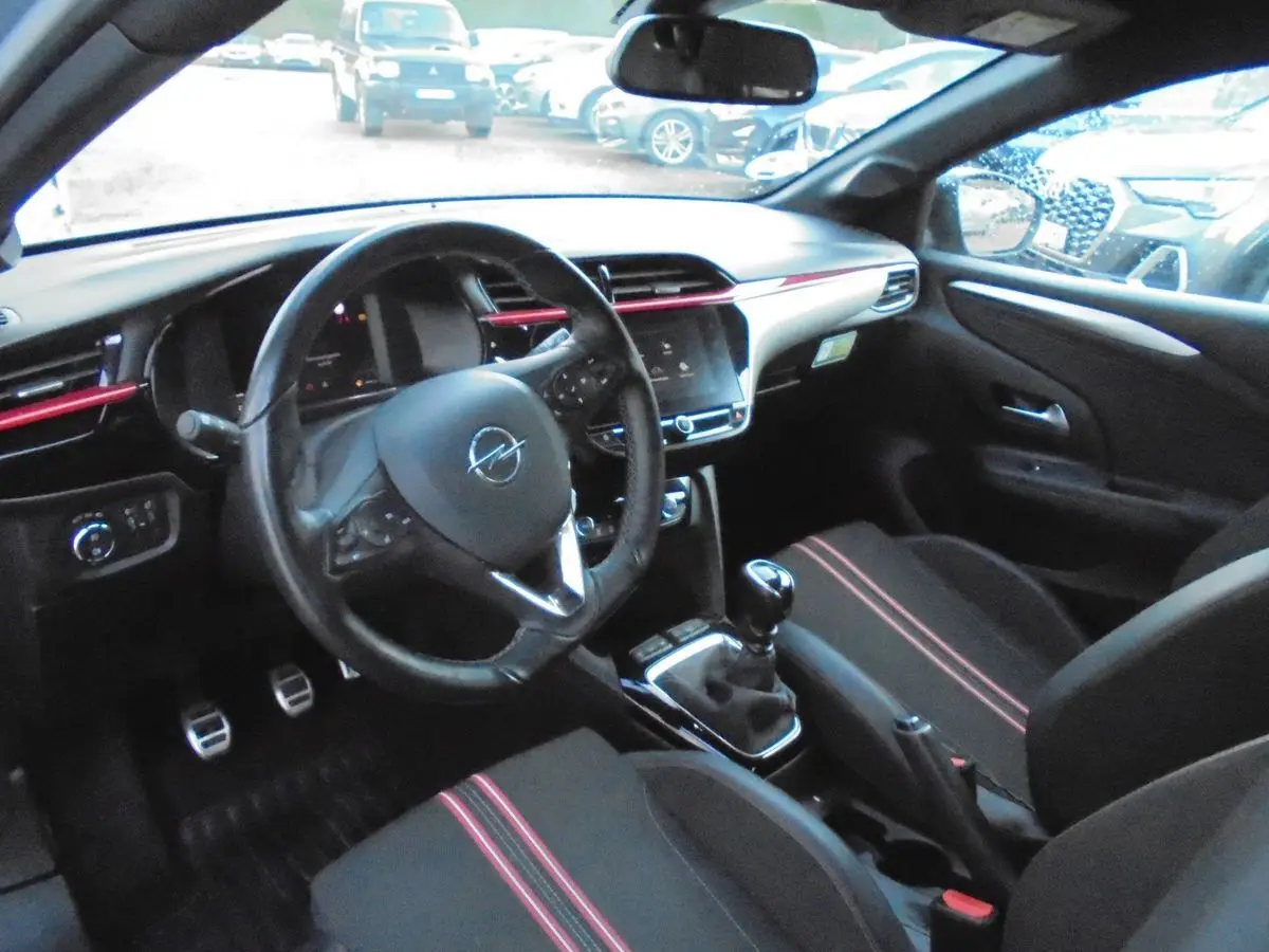 Intérieur de l'Opel Corsa 1.2T 100 CH GS-Line 2021, vue côté conducteur, sièges noirs avec surpiqûres rouges.