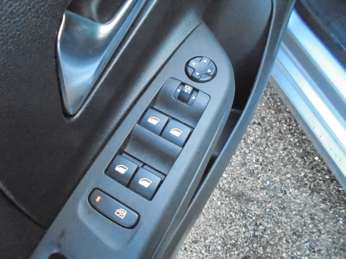 Gros plan sur les commandes des vitres électriques côté gauche de la porte avant d'une Opel Corsa gris quartz métal.