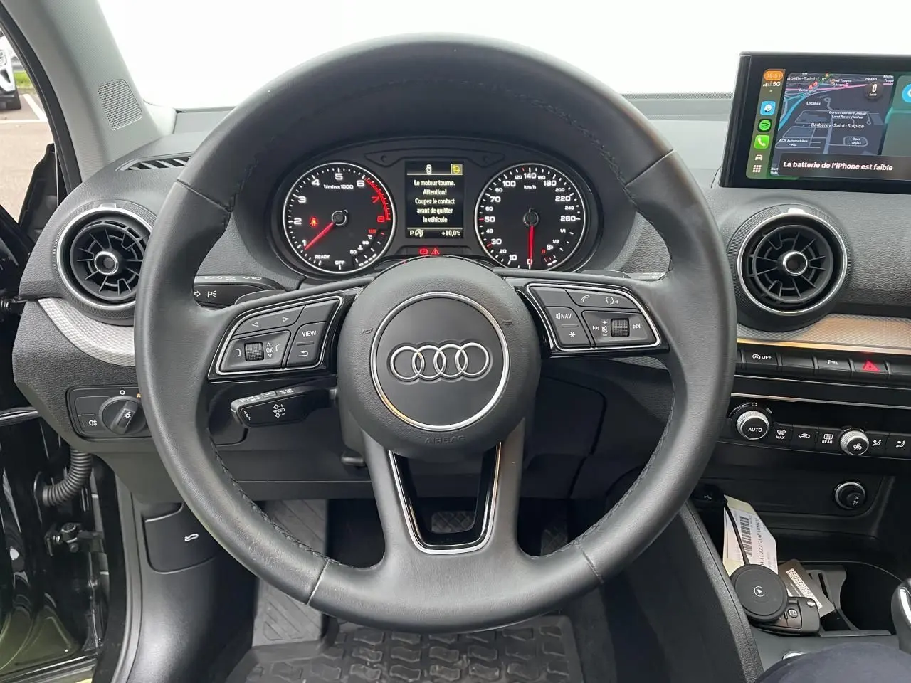 Vue intérieure centrée sur le volant cuir multifonction et le tableau de bord numérique de l'Audi Q2 2023.