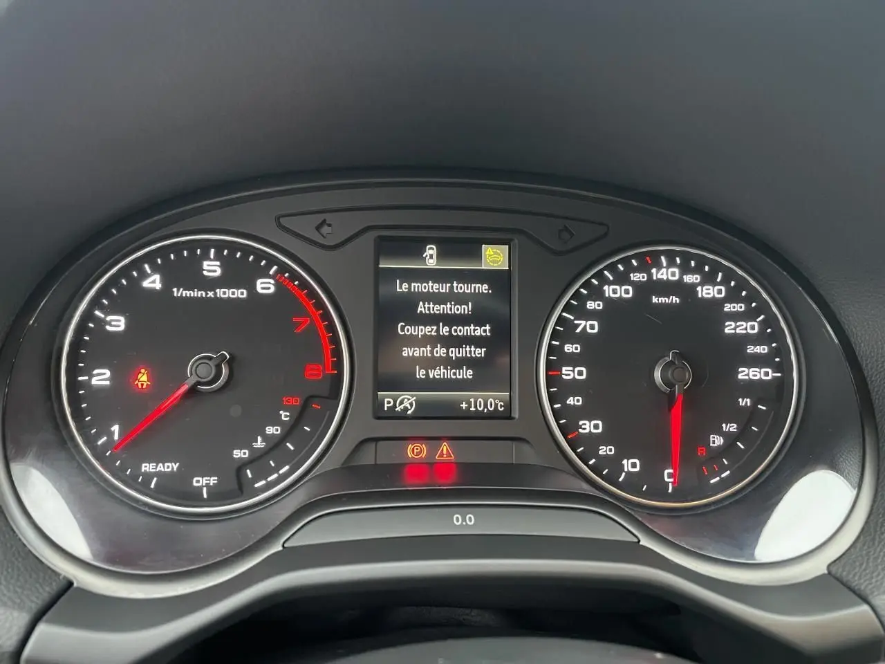 Tableau de bord d'Audi Q2 2023 avec compte-tours, vitesse, et écran central affichant un message d'alerte moteur.