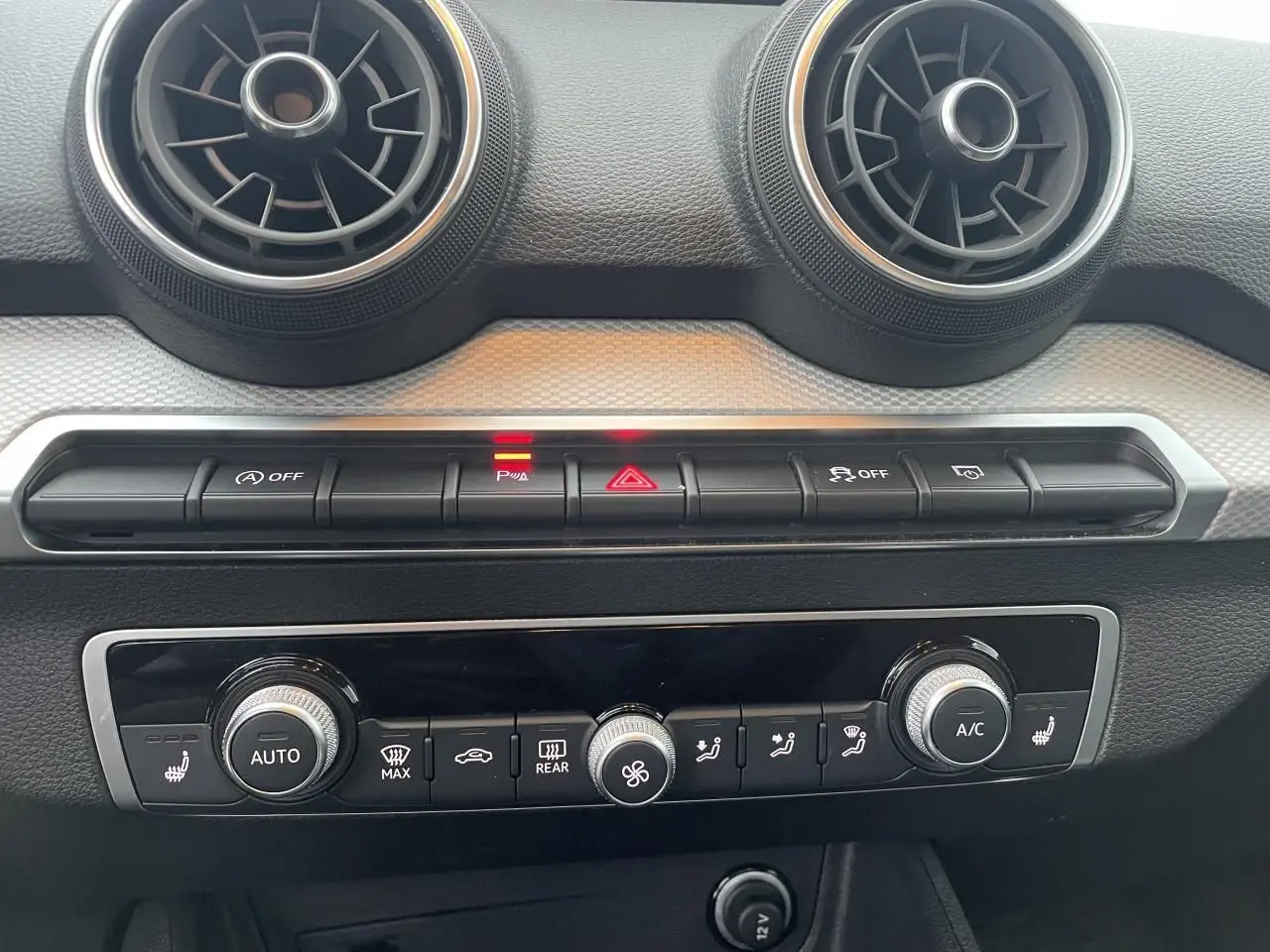 Vue rapprochée de la console centrale de l’Audi Q2 35 TFSI 2023, avec commandes climatisation et aérateurs ronds.