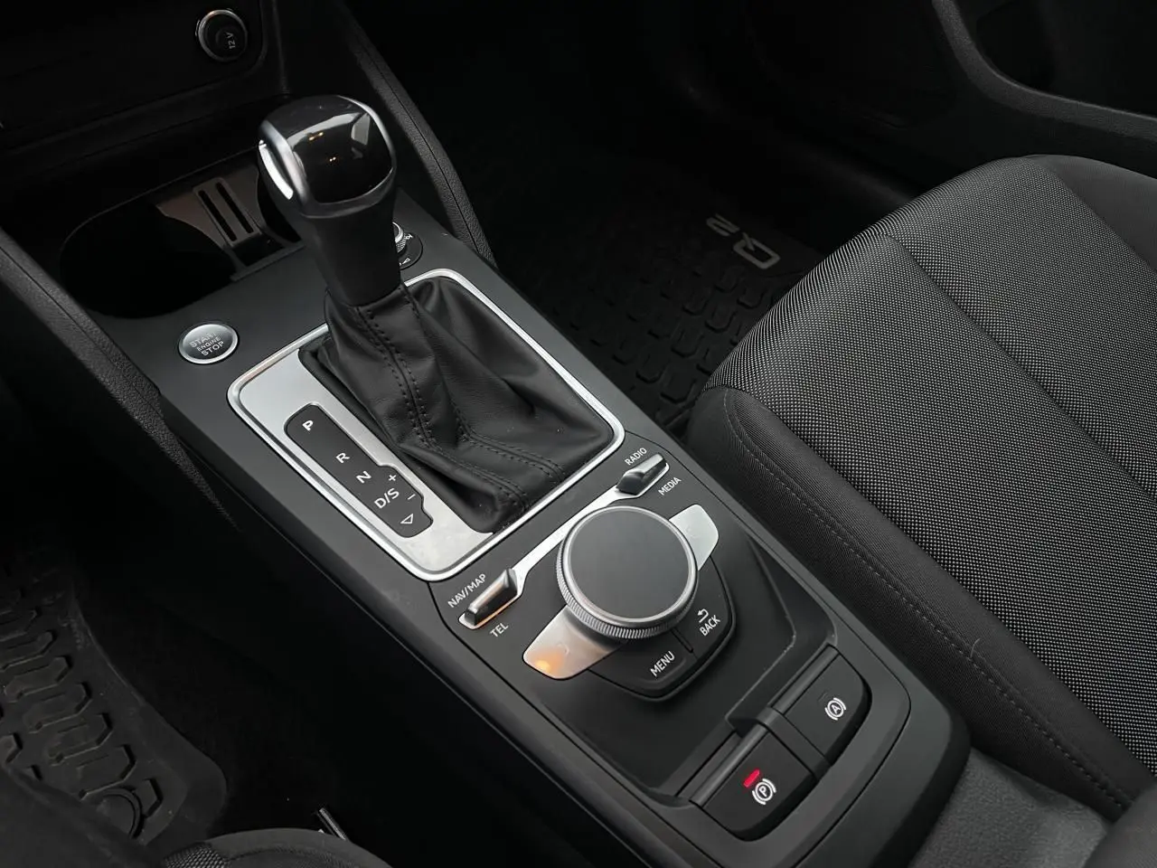 Vue rapprochée de la console centrale noire de l'Audi Q2 2023 avec levier de vitesse automatique et molette MMI.