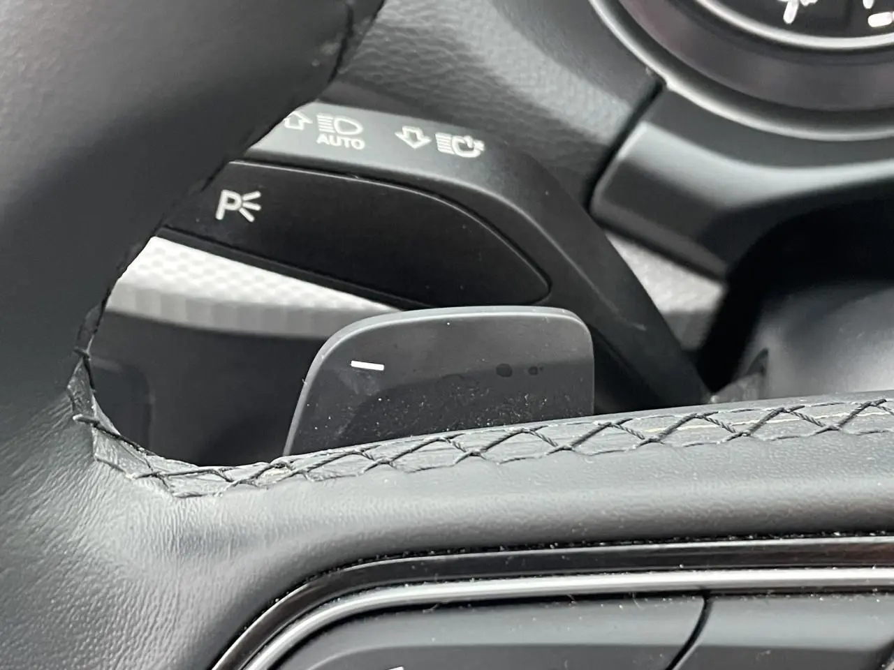 Gros plan sur la palette de changement de vitesse derrière le volant cuir noir de l'Audi Q2 35 TFSI 2023.