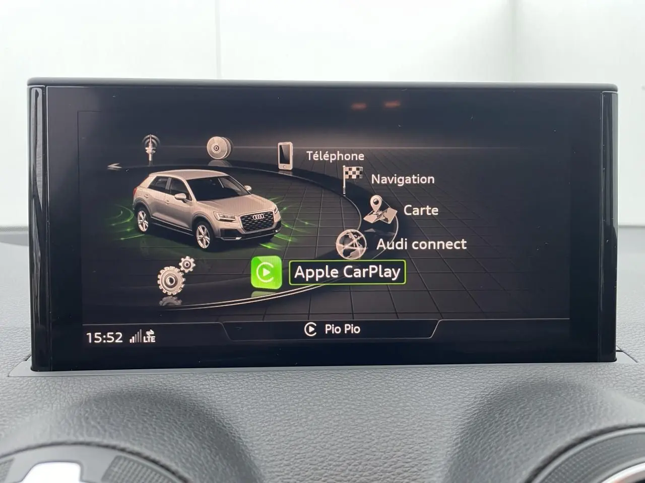 Écran central de l'Audi Q2 2023 affichant le menu Apple CarPlay avec une miniature du SUV gris clair.