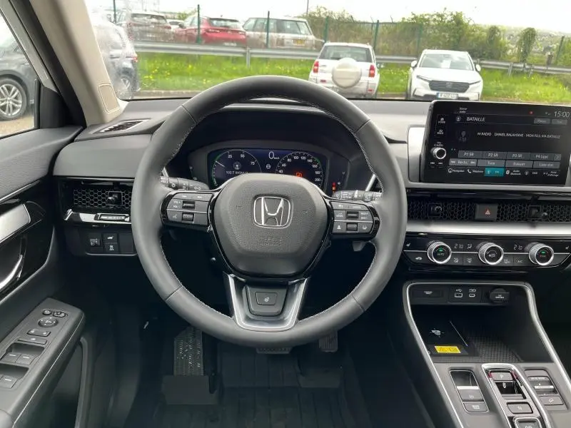 Vue intérieure centrée sur le volant cuir noir et le tableau de bord digital du Honda CR-V 2024 hybride.