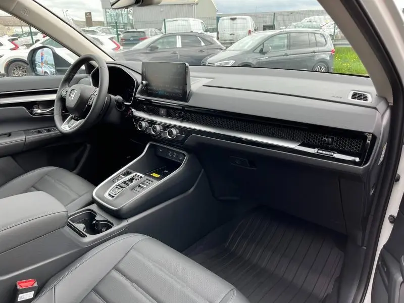 Vue intérieure côté passager du tableau de bord et console centrale noire du Honda CR-V 2024 blanc nacré.
