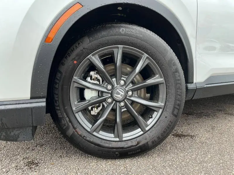 Gros plan sur la roue avant gauche du Honda CR-V blanc nacré, avec jante alliage gris foncé et pneu Michelin.