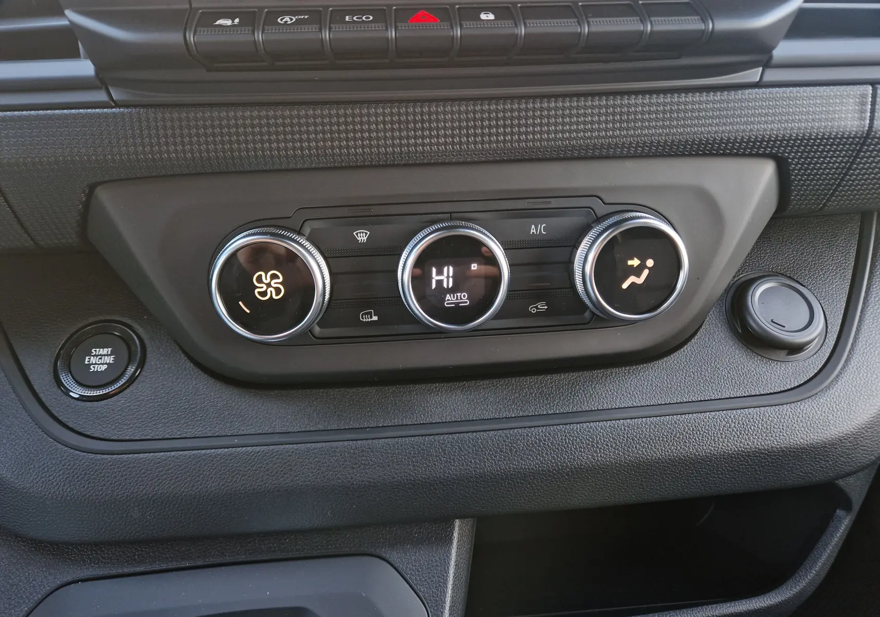Vue rapprochée du tableau de bord du Renault Trafic Fourgon 2025, avec commandes de climatisation et bouton start/stop.