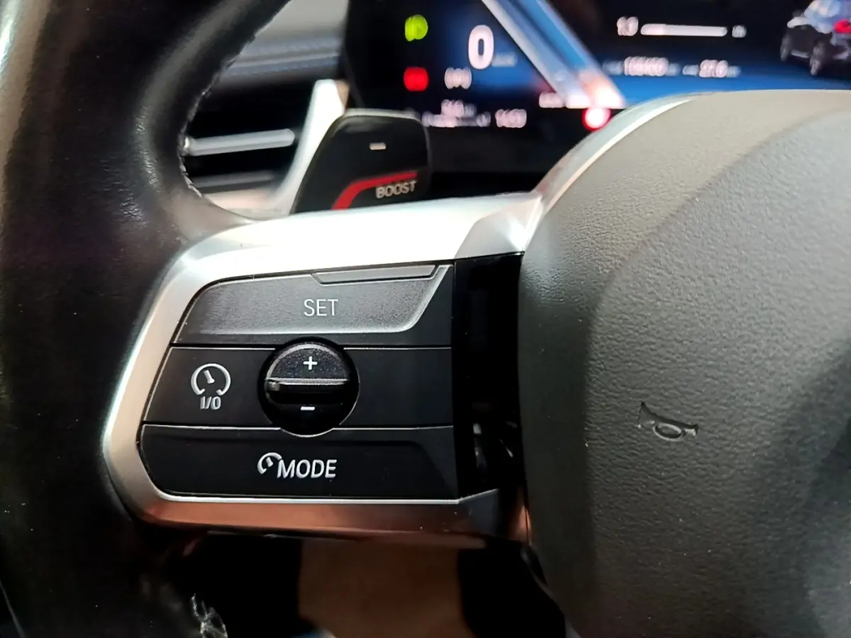 Gros plan sur les commandes de régulateur de vitesse au volant cuir noir de la BMW X1 xDrive23i M Sport 2023.