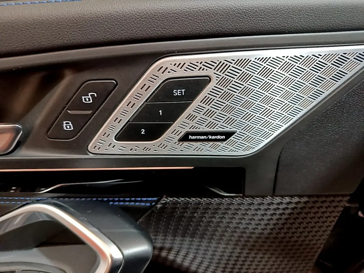 Détail intérieur côté conducteur BMW X1 noir 2023 montrant les commandes de mémoire siège et haut-parleur Harman/Kardon.