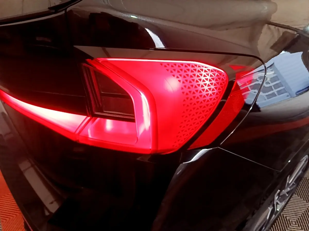 Gros plan sur le feu arrière gauche rouge du BMW X1 xDrive23i M Sport noir, soulignant ses motifs triangulaires distinctifs.