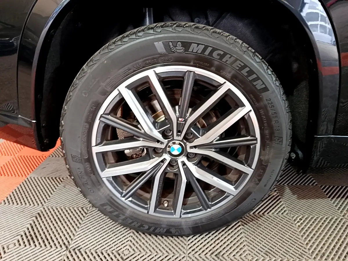 Gros plan sur la roue avant gauche noire du BMW X1 xDrive23i M Sport avec jante alliage et pneu Michelin