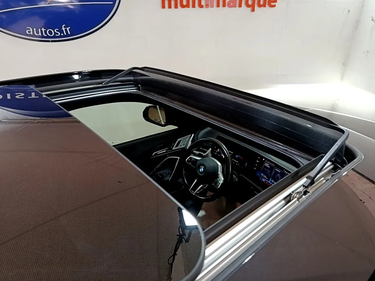 Vue plongeante sur l'intérieur noir du BMW X1 xDrive23i M Sport 2023 à travers son toit ouvrant panoramique.