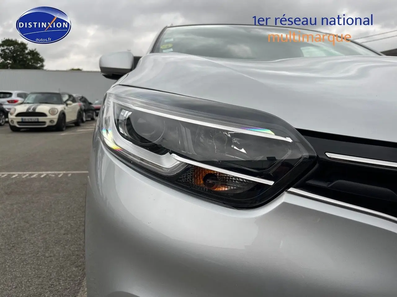 Gros plan sur le phare avant gauche du Renault Kadjar gris platine, soulignant la calandre et le capot lisse.
