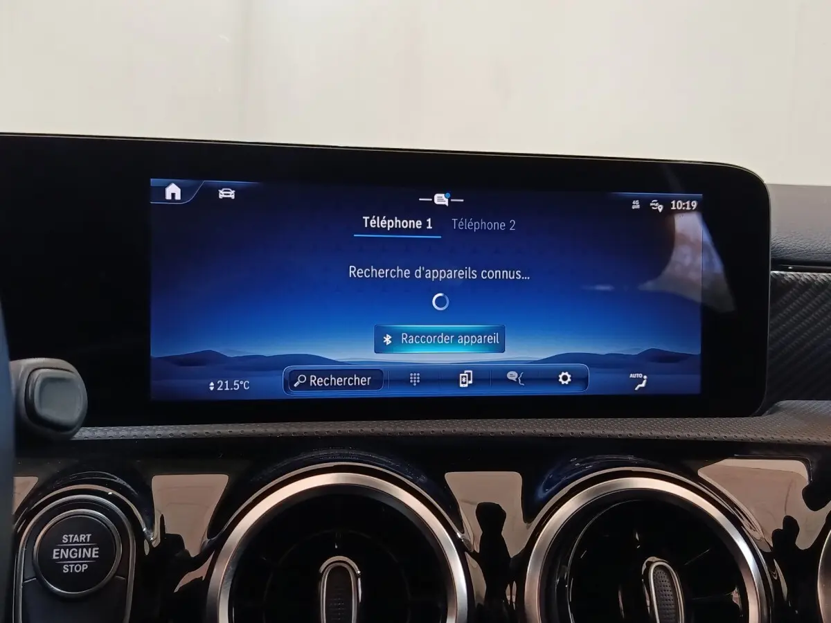 Vue intérieure du tableau de bord de la Mercedes Classe A 250 e Business Line 2023 avec écran tactile central et aérateurs ronds chromés.