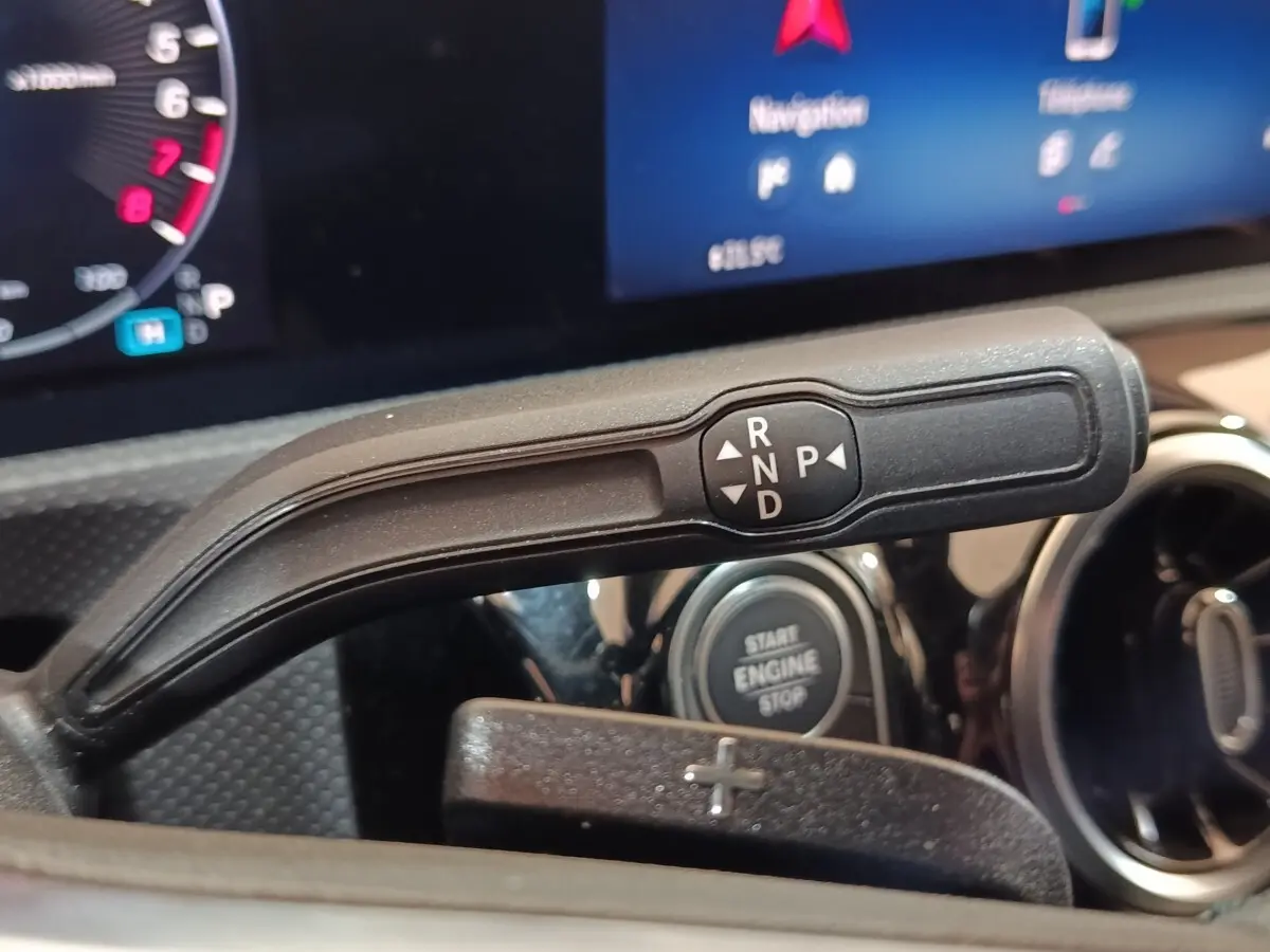 Gros plan sur la commande de boîte automatique noire avec levier de vitesses et bouton start/stop dans un Mercedes Classe A gris clair.