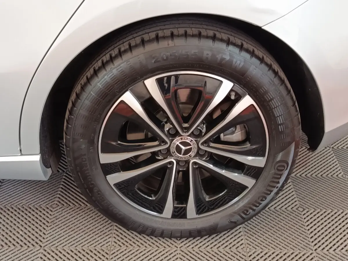 Gros plan sur la roue avant droite gris clair d'une Mercedes Classe A 250 e Business Line avec jante alliage noir et argent.