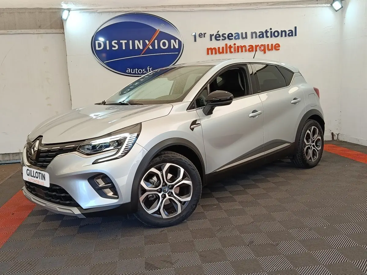 Renault Captur Intens E-TECH gris clair en 3/4 avant droit, avec jantes alliage et feux LED allumés.