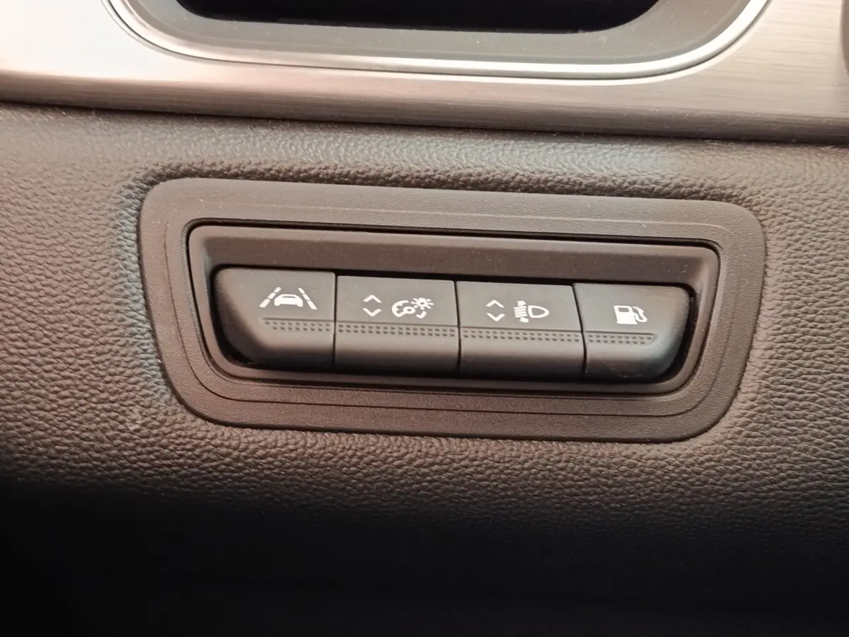 Gros plan sur les boutons de commande d'assistance et éclairage du tableau de bord du Renault Captur gris clair Intens E-TECH.