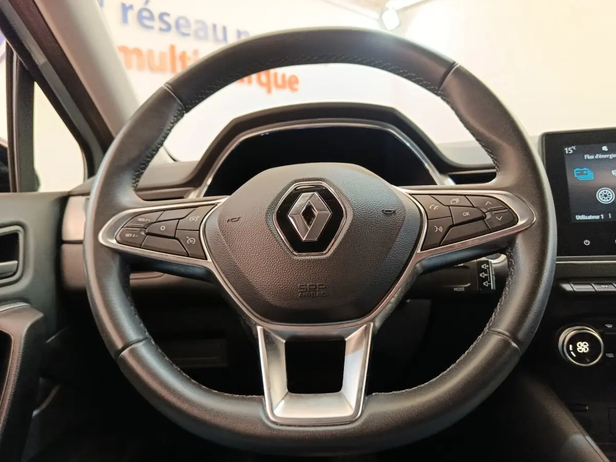 Vue rapprochée du volant en cuir noir du Renault Captur Intens E-TECH 2021 avec commandes intégrées et logo central.