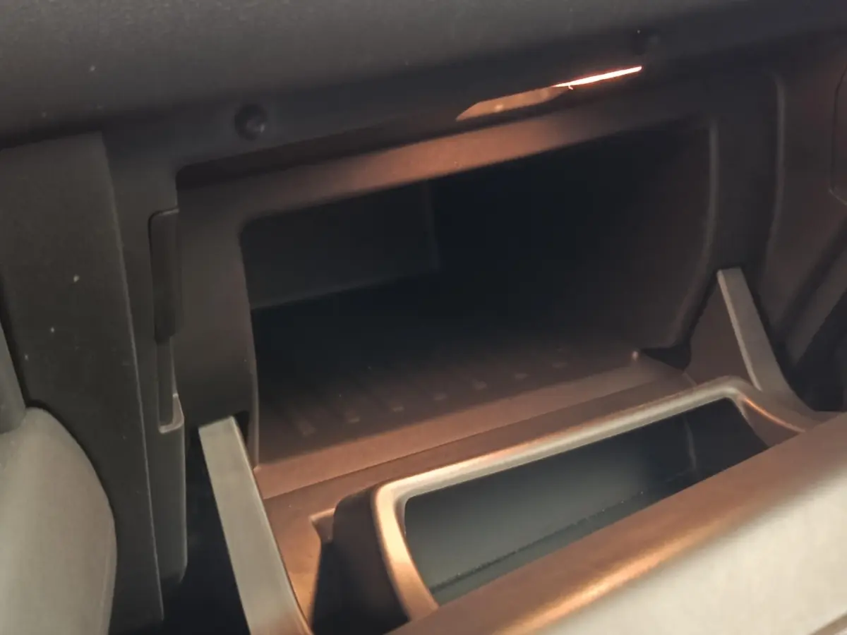 Gros plan sur la boîte à gants ouverte de la Renault Captur Intens E-TECH 2021, intérieur noir avec éclairage ambiant.