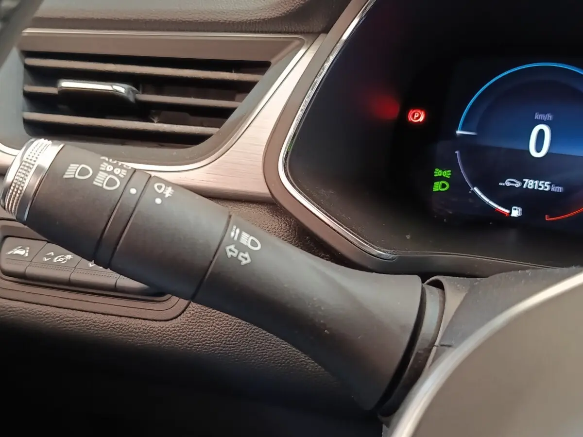 Gros plan sur la commande des feux et le combiné d'instruments numérique du tableau de bord du Renault Captur gris clair.