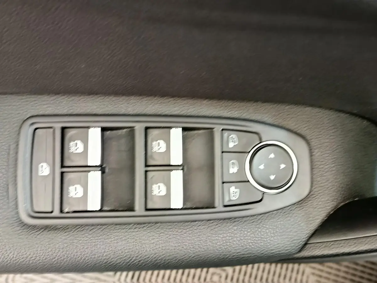 Panneau de commandes des vitres électriques et rétroviseurs sur la porte côté conducteur d'un Renault Captur gris clair.