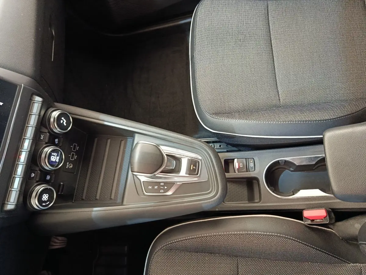 Vue intérieure centrée sur la console centrale et levier de vitesse automatique du Renault Captur gris clair 2021.