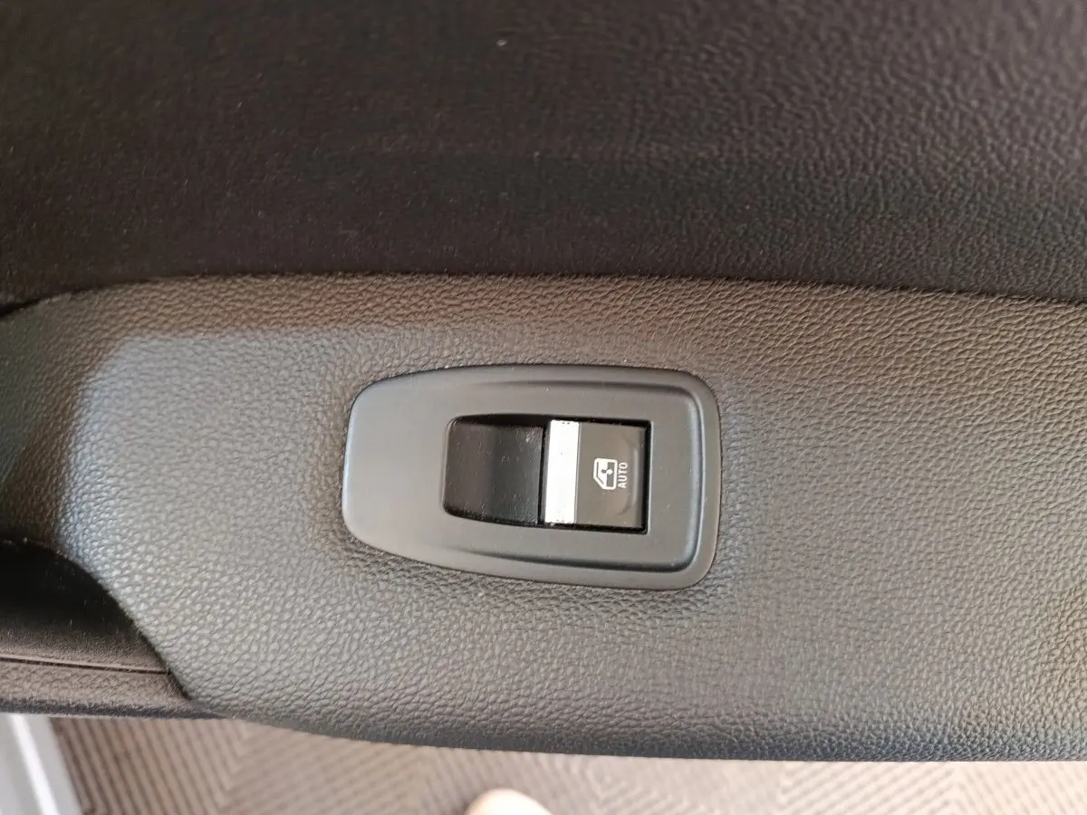 Gros plan sur l'interrupteur de lève-vitre automatique côté conducteur du Renault Captur gris clair Intens E-TECH 2021.