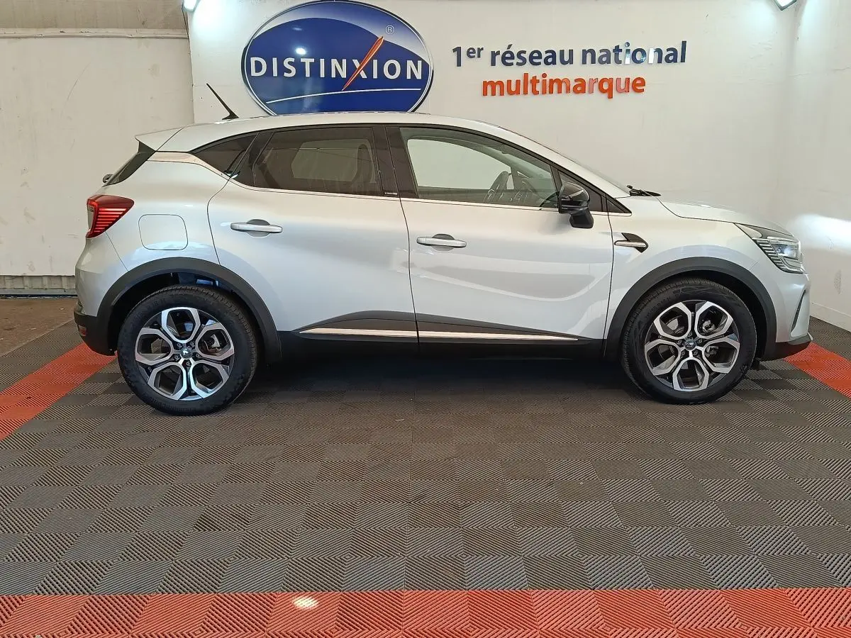 Profil droit d'un Renault Captur Intens E-TECH Plug-in 160 gris clair, avec jantes alliage et détails noirs contrastants.