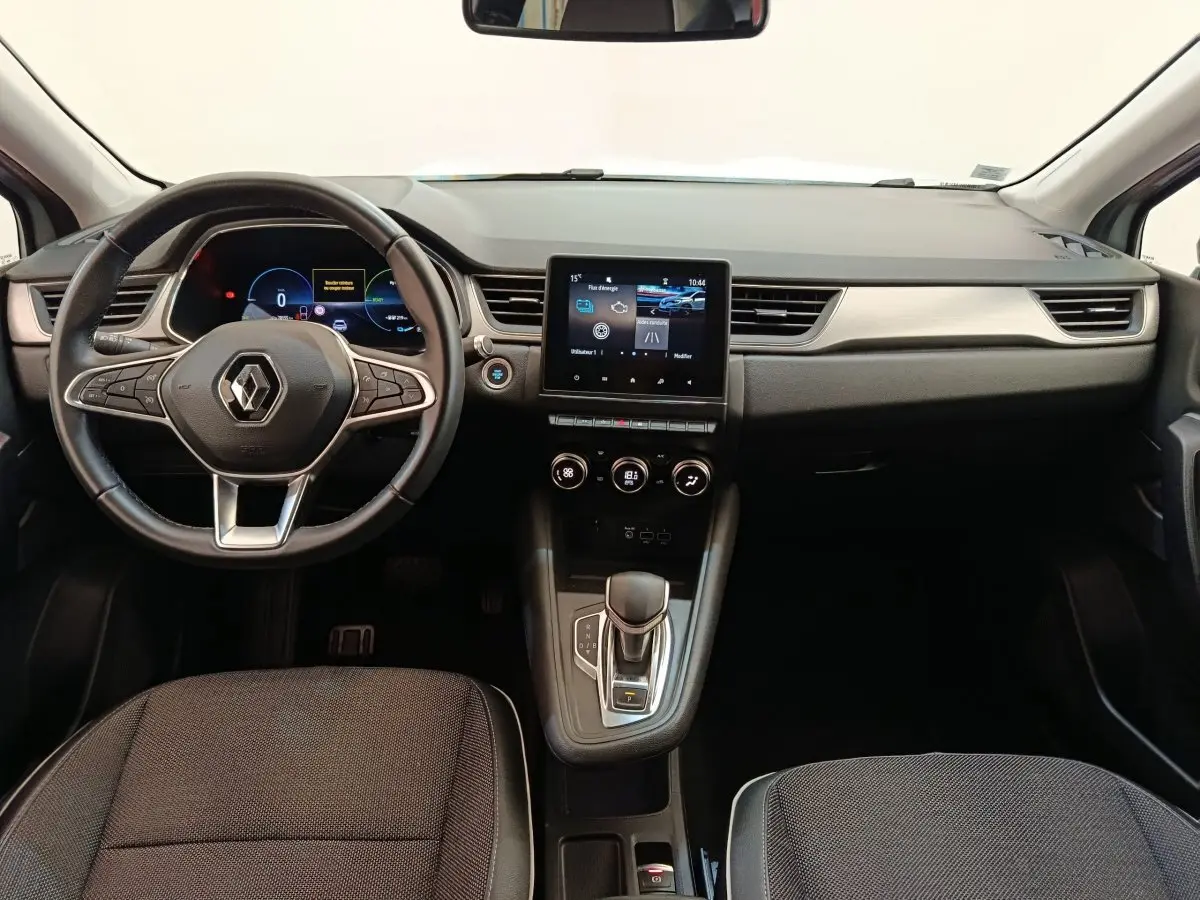 Vue intérieure avant du Renault Captur Intens E-TECH 2021, tableau de bord noir avec écran tactile central et volant multifonctions.