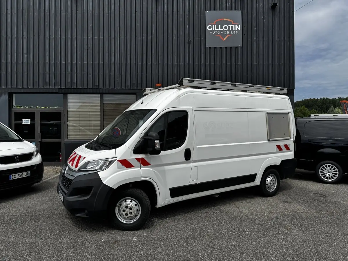 Vue 3/4 avant droit d’un utilitaire Citroën Jumper blanc avec bandes rouges réfléchissantes et galerie sur le toit.