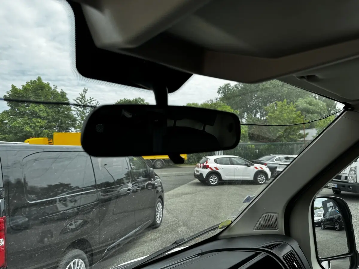 Vue intérieure depuis le siège conducteur du Citroën Jumper blanc, avec rétroviseur et tableau de bord partiellement visibles.