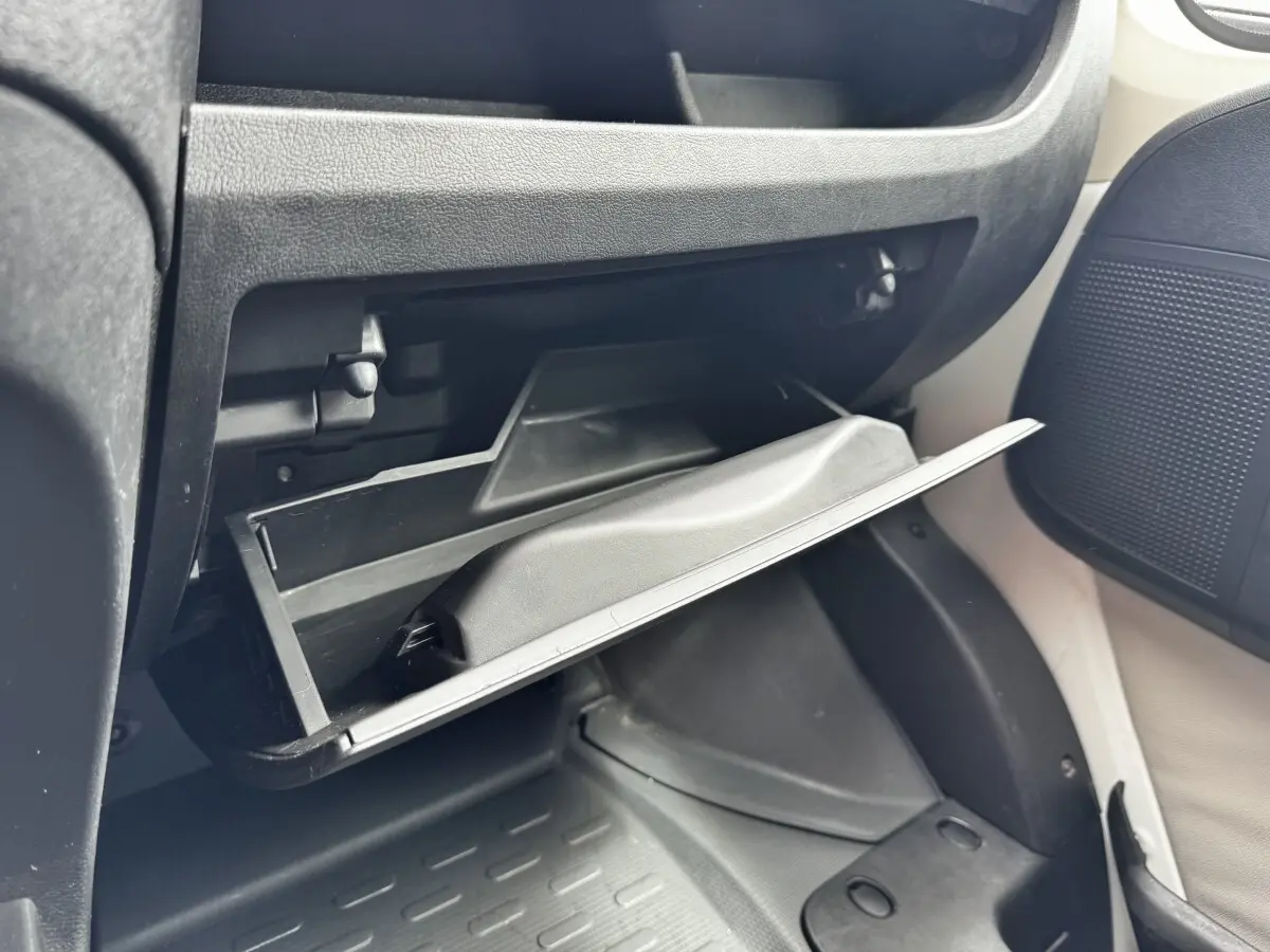 Gros plan sur la boîte à gants ouverte côté passager du Citroën Jumper blanc, intérieur noir et beige.