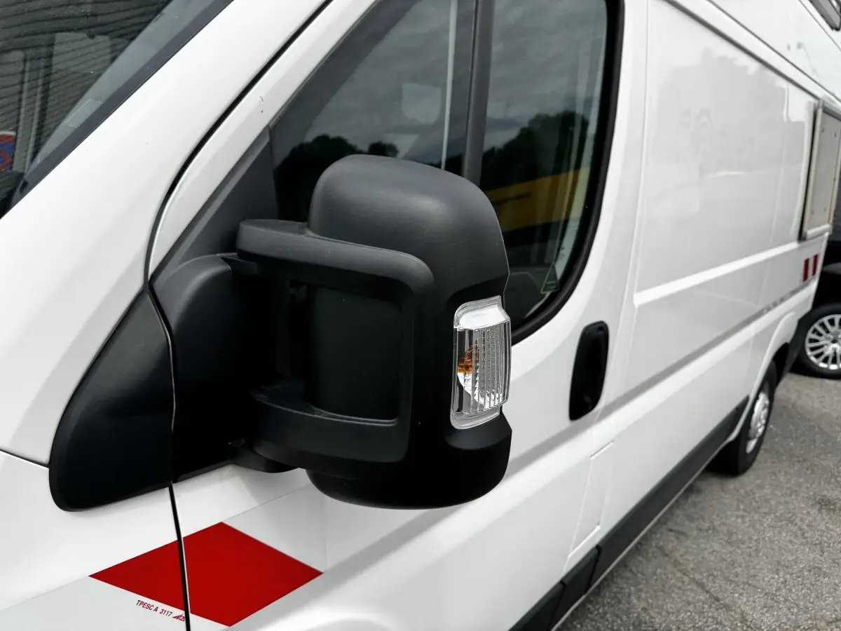 Vue de côté droit rapprochée sur le rétroviseur noir d’un utilitaire blanc Citroën Jumper 2019 avec marquage rouge.