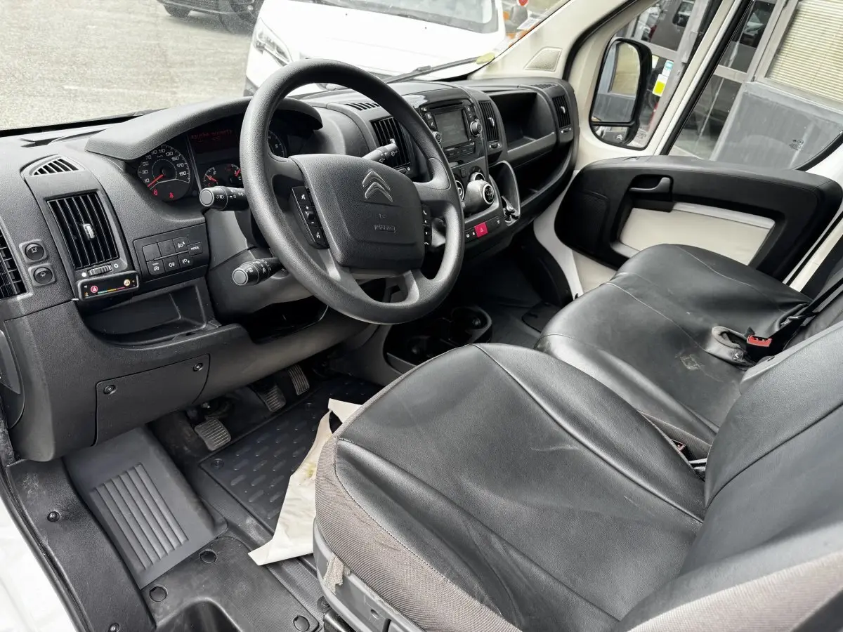 Vue intérieure côté conducteur du Citroën Jumper 2019, volant multifonctions, sièges noirs en cuir, tableau de bord et console centrale visibles.