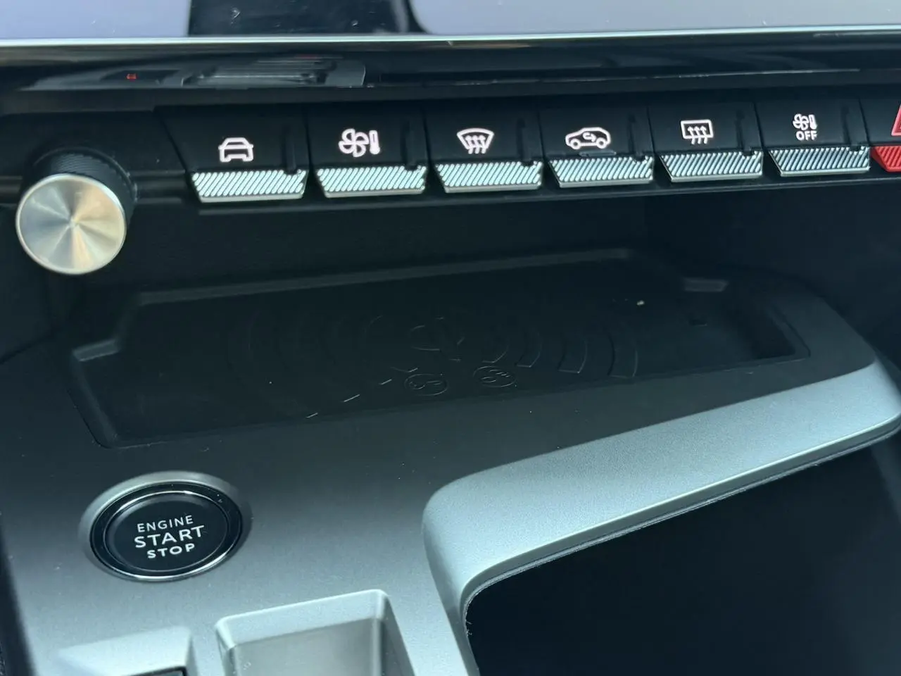 Vue rapprochée de la console centrale du Peugeot 308 Hybrid 2025, montrant le bouton start/stop et le chargeur induction.