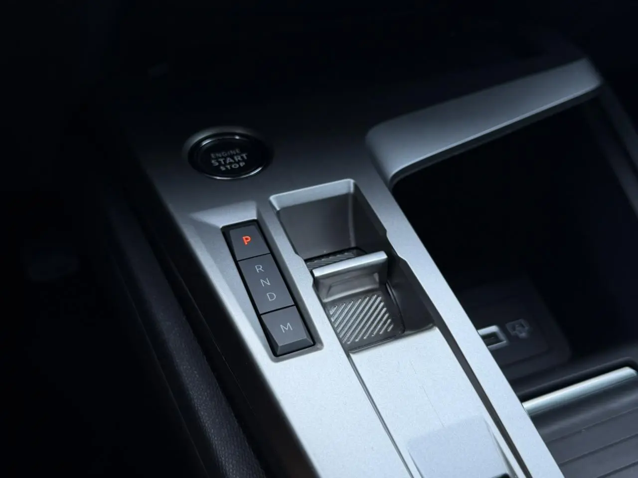Gros plan sur la console centrale grise avec boutons de boîte auto et bouton start/stop du Peugeot 308 Hybrid 2025.