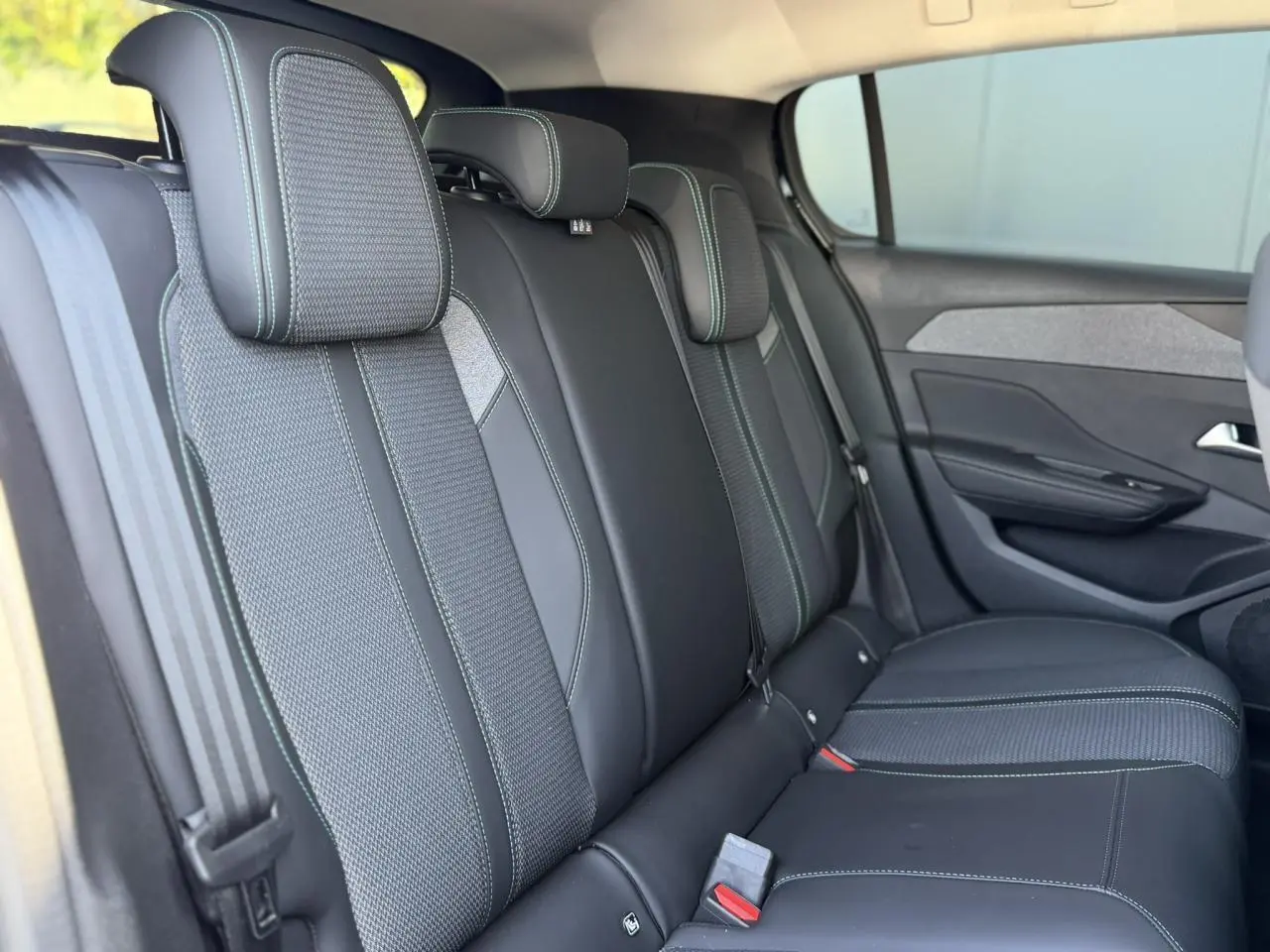 Vue intérieure côté droit des sièges arrière en sellerie tri matières noire avec surpiqûres bleues de la Peugeot 308 Hybrid 2025