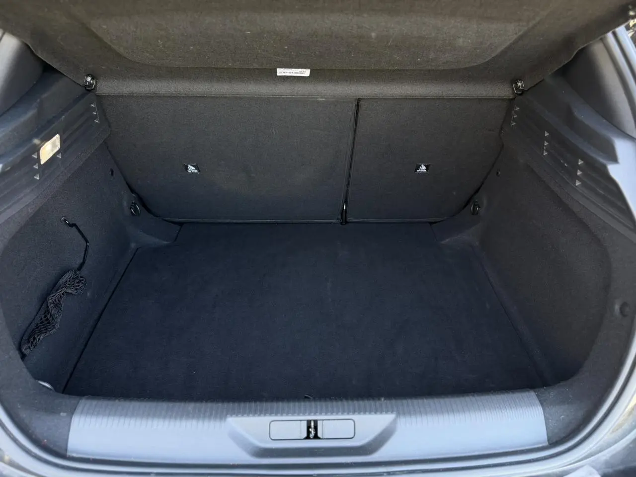 Coffre vide vu de l'arrière d'une Peugeot 308 Hybrid 145 e-DSC6 Allure noir Perla, intérieur noir.
