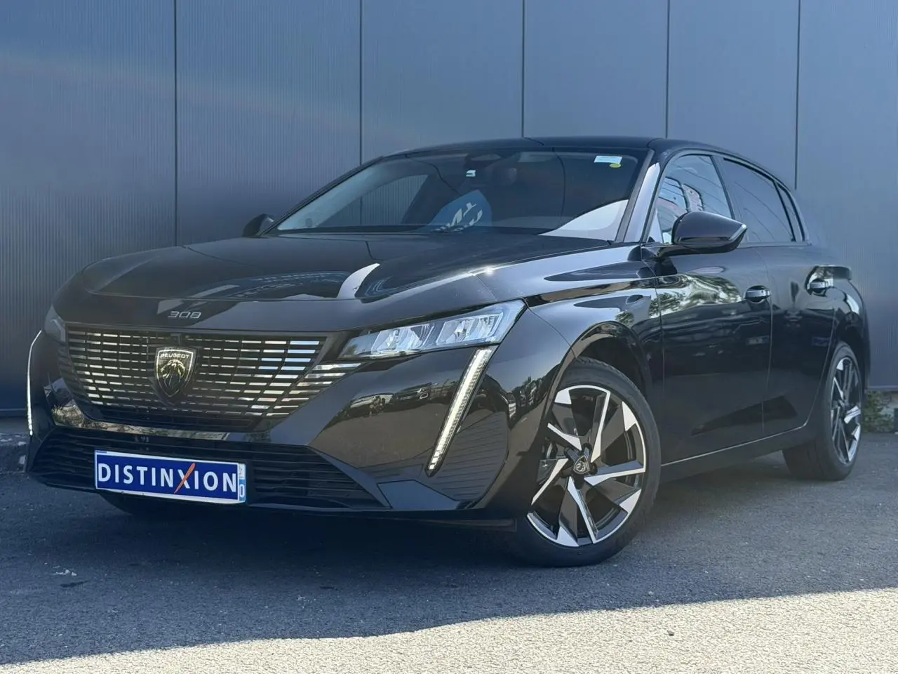 Peugeot 308 Hybrid 145 noir Perla vue 3/4 avant droit, avec jantes alliage et calandre distinctive.