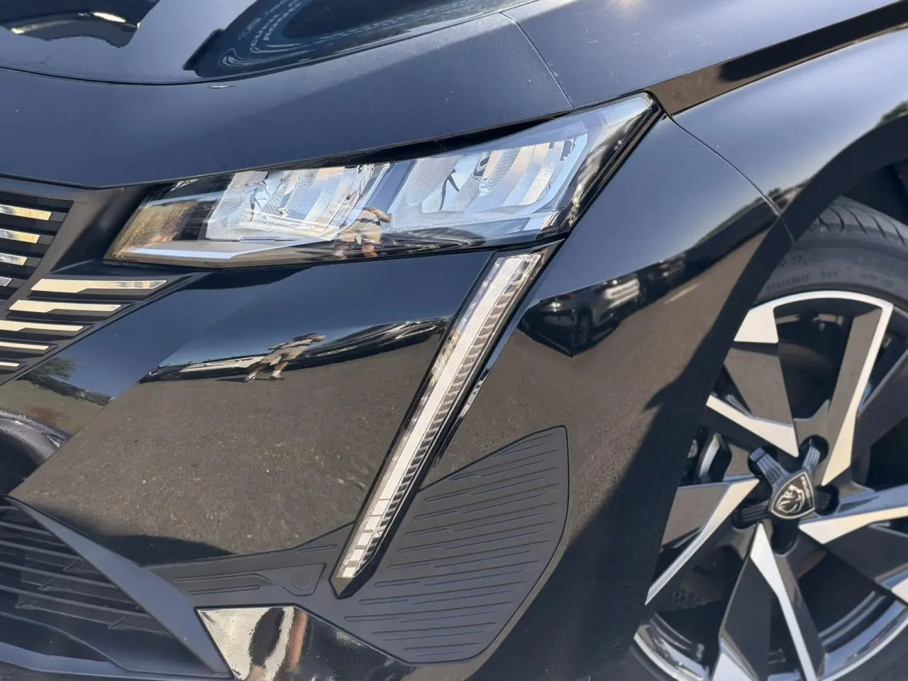 Gros plan sur l'avant droit noir Perla de la Peugeot 308 Hybrid avec feux LED et jante alliage 17 pouces.