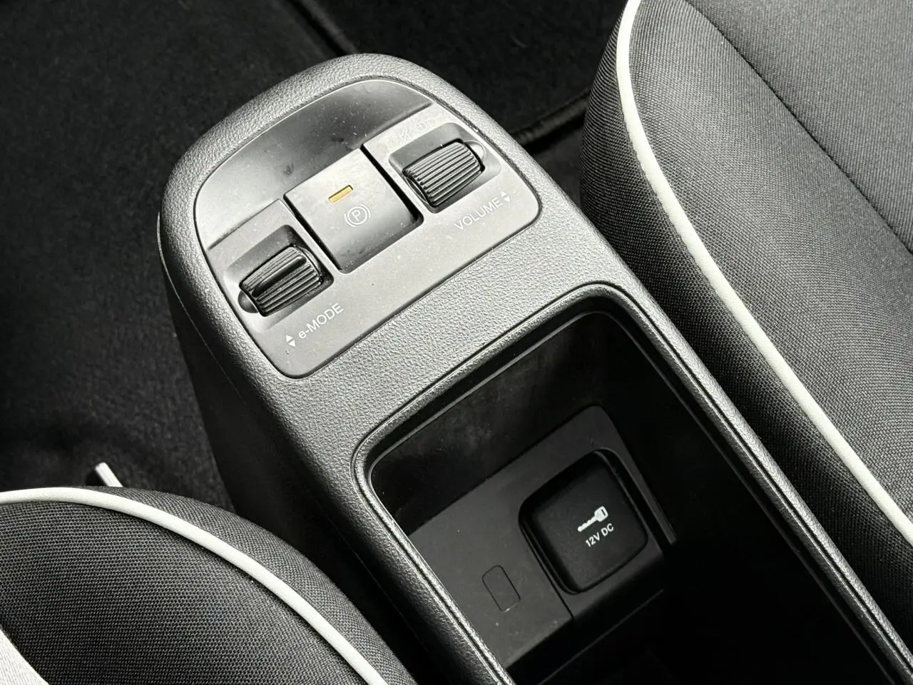 Gros plan sur la console centrale noire de la Fiat 500 électrique avec commandes e-mode et frein à main électrique.