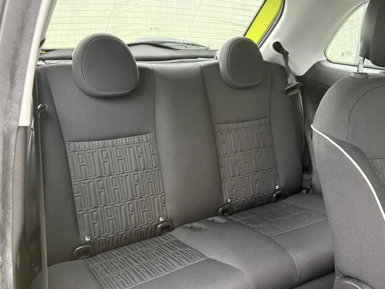 Vue intérieure arrière des sièges noirs avec motif FIAT embossé dans une Fiat 500 électrique jaune Acid 2024.